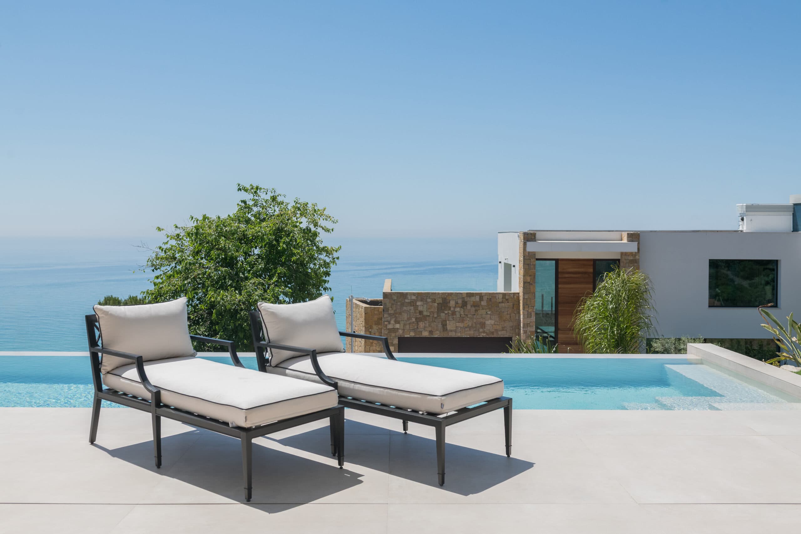 Tumbonas de diseño en una terraza sobre el Mediterráneo, amuebladas por BANQA